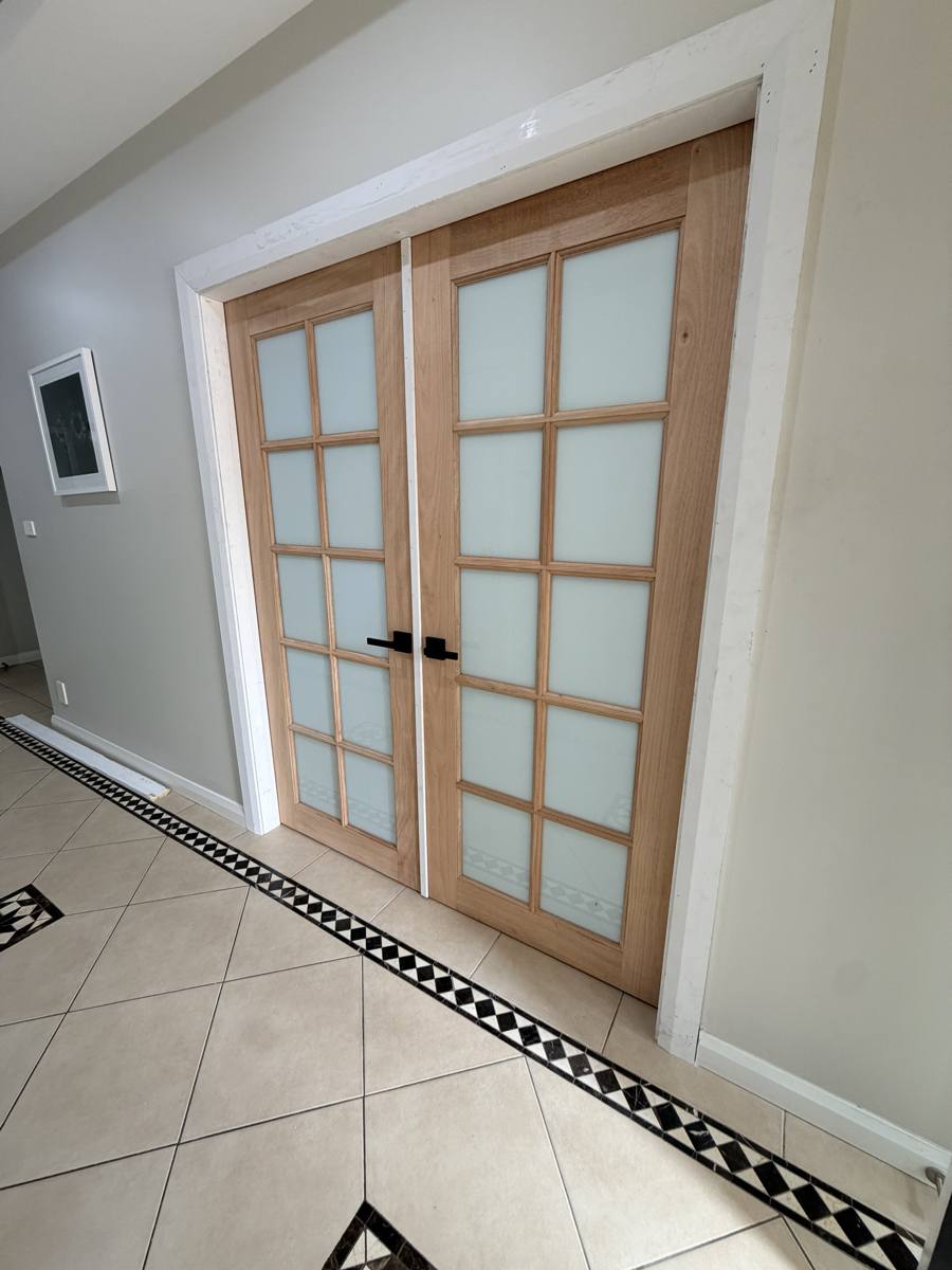 Timber French doors viewed from an angle in a tiled hallway