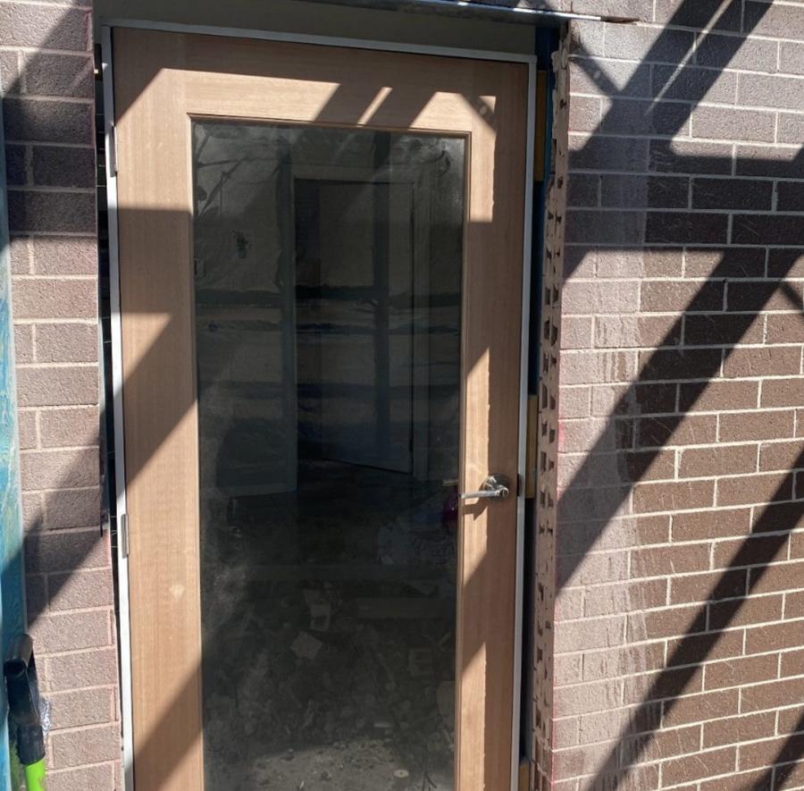New glazed timber door installed in a new opening cut through a brick wall