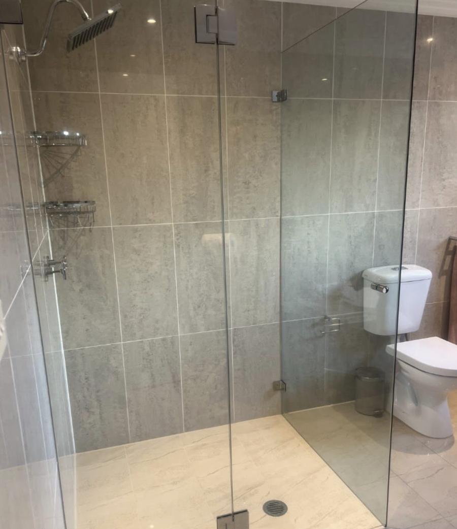 Frameless L-shaped glass shower screen with chrome hinges